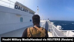 Хутски боец ​​стои на товарния кораб "Галакси Лийдър" в Червено море. Снимката е публикувана на 20 ноември 2023 г.