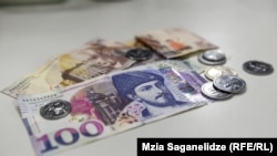 საქართველოს ეროვნული ვალუტის 100-ლარიანი კუპიურა და მონეტები. 