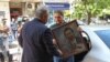 Алекбер Абил от младежката структура на ДПС-Доган държи портрет на почетния лидер на движението Ахмед Доган. Това се случва, докато служители на областната администрация в София запечатват партийната централа на ДПС, 19 май 2025 г.