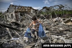 Женщина собирает остатки имущества у своего разрушенного ракетным обстрелом дома. Славянск, Украина, 1 июня 2022 года