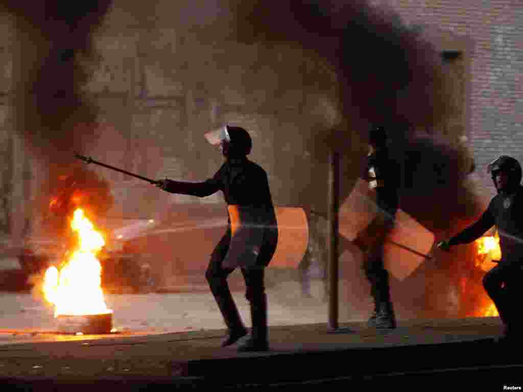 Riot police walk past a burning barricade during clashes in Cairo on January 26.