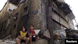 Сириянын Хомс шаарындагы талкаланган үйдүн жанында отурган балдар
