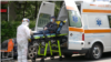 Romanian paramedics transport a patient with covid-19 symptoms to a hospital
