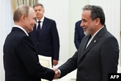 Президент России Владимир Путин (слева) и министр иностранных дел Ирана Аббас Аракчи пожимают друг другу руки во время встречи в Кремле, Москва, 23 июня 2025 года