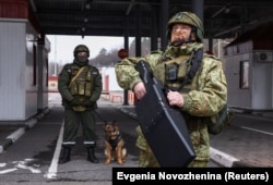 Beloruski vojnik stoji s uređajem protiv dronova na graničnom prelazu s Ukrajinom.