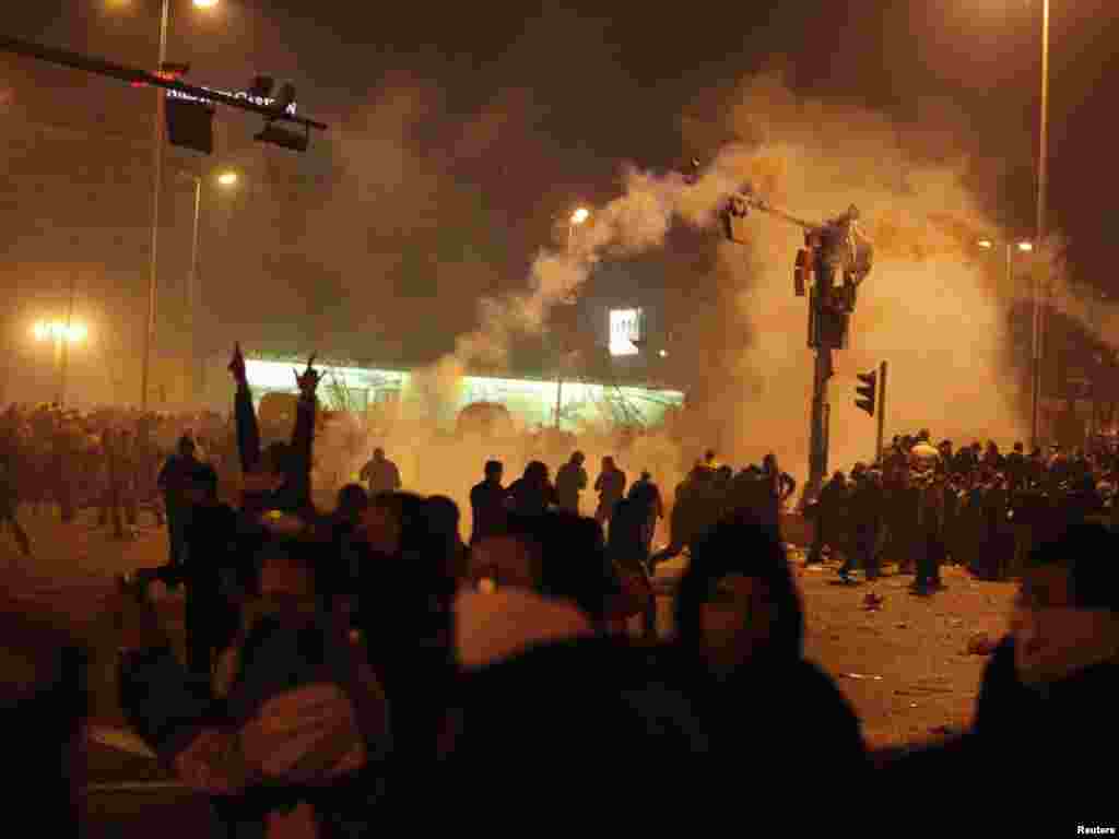 Antigovernment demonstrators walk away after tear gas was released on January 25 in Cairo.