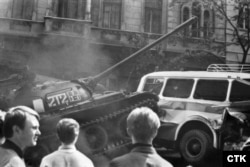 Un tanc sovietic intră din plin într-un autobuz folosit de protestatari ca o baricadă pentru a bloca forțele sovietice să ajungă la sediul radioului cehoslovac.