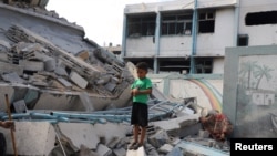 Një djalë palestinez qëndron mbi rrënoja në një shkollë të OKB-së, ku njerëzit e zhvendosur po strehoheshin, pasi u godit nga sulmet ajrore izraelite gjatë natës në lagjen Zeitoun në Qytetin e Gazës, 1 tetor 2025.
