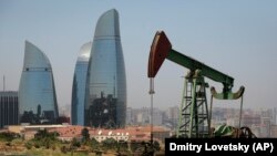 AZERBAIJAN -- Skyscrapers stand in the background as an oil pump works a nearby hill in Baku