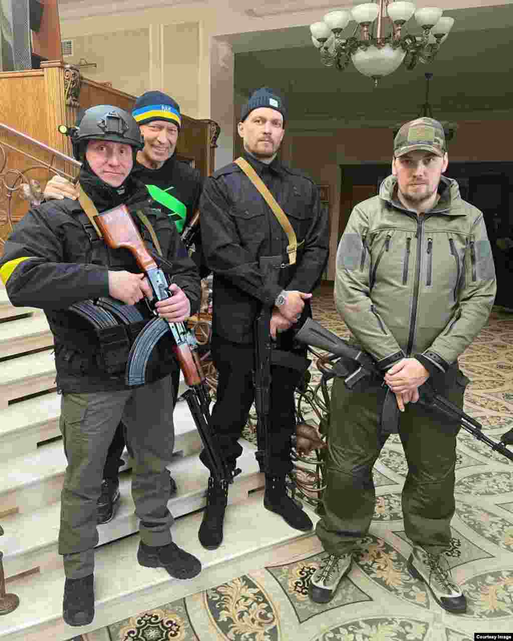 Усик (в центре справа) вооружен собственным оружием в первые дни российского масштабного вторжения. В феврале 2022 года Усик находился в Великобритании, когда жена прислала ему смс-сообщение о том, что Россия осуществила масштабное вторжение в Украину. Боксер немедленно вылетел в Польшу, затем поехал в Киев, где вступил в батальон территориальной обороны