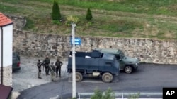 Група въоръжени маскирани мъже стоят пред манастира Банска в Северно Косово в неделя, 24 септември 2023 г.